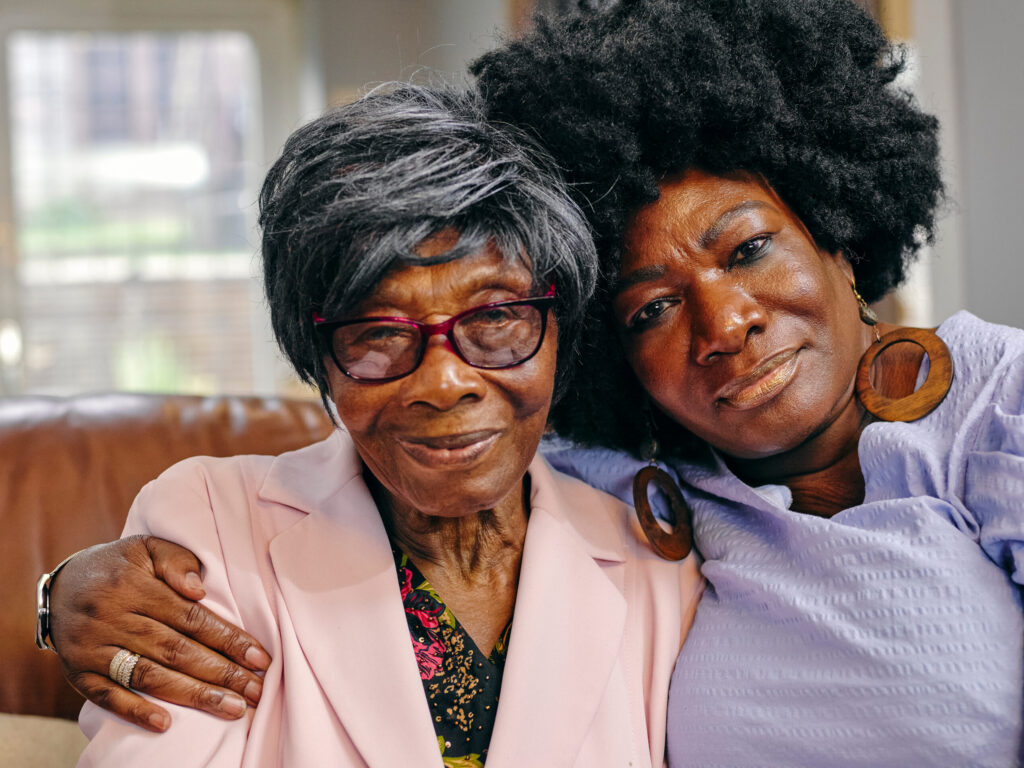 Portrait mature woman embracing senior mother on sofa